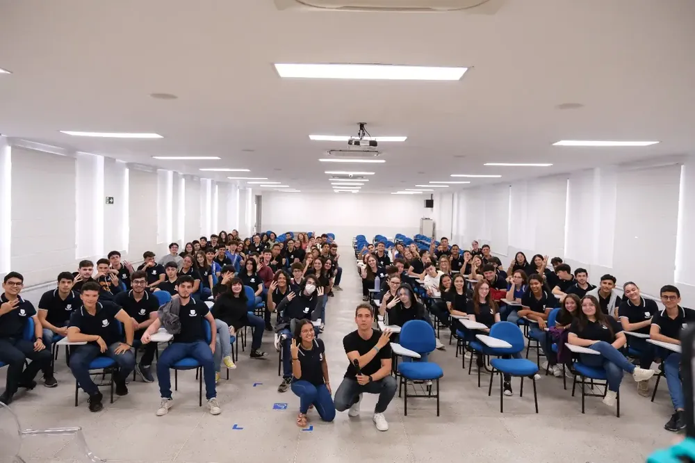 Auditório lotado de alunos de escola parceira em um evento da AM